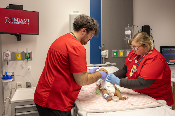 2 nursing students assisting a simulation baby.