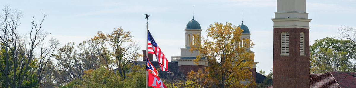 Harrison hall spire with the Bell Tower and American Flags in the forground
