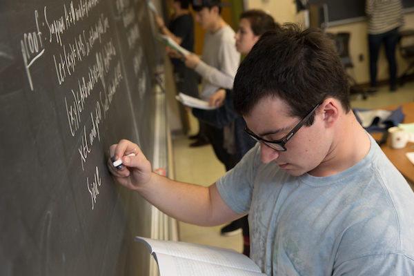 Student working on a math problem at a chalk board