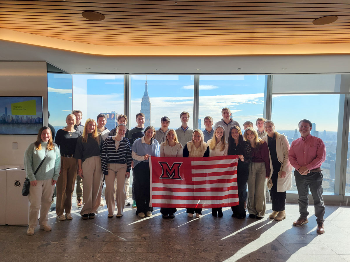 accountancy students in building holding Miami flag