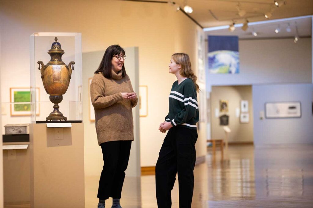 faculty and student walking through an art exhibition