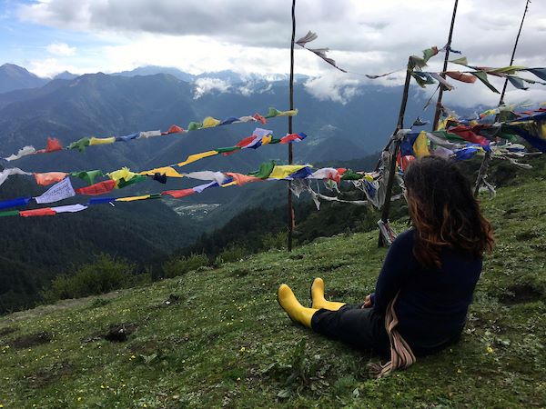 student siting on a hillside in the Himalayas during a study abroad experience