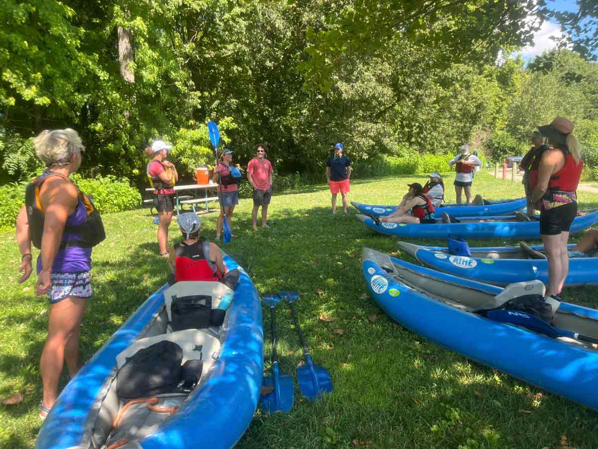 students standing next to inflatable rafts listening to instructions