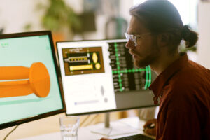 man working at desk with two computer monitors, each with lab results and equipment images