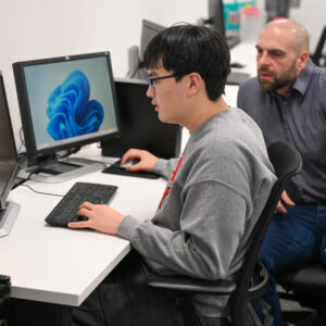 student working on a computer with a faculty member