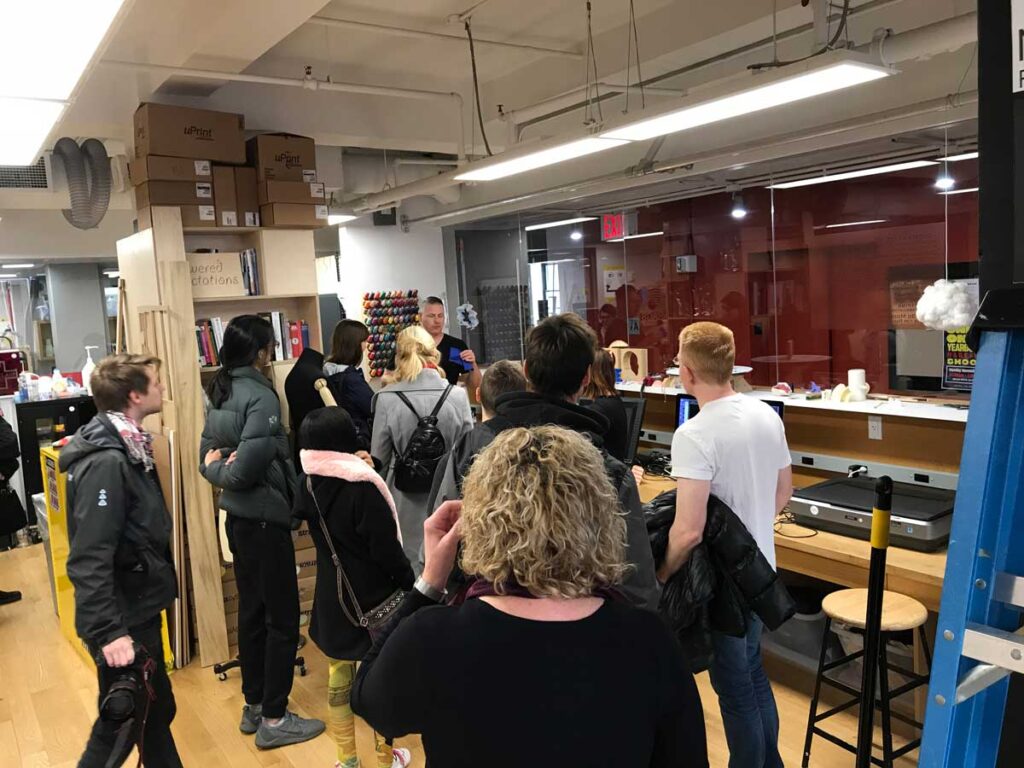 Miami University students tour a creative lab filled with tools, materials, and 3D printing equipment related to animation design.