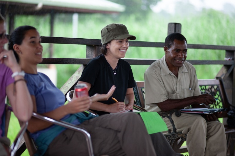 People talking while sitting on a deck in the forest
