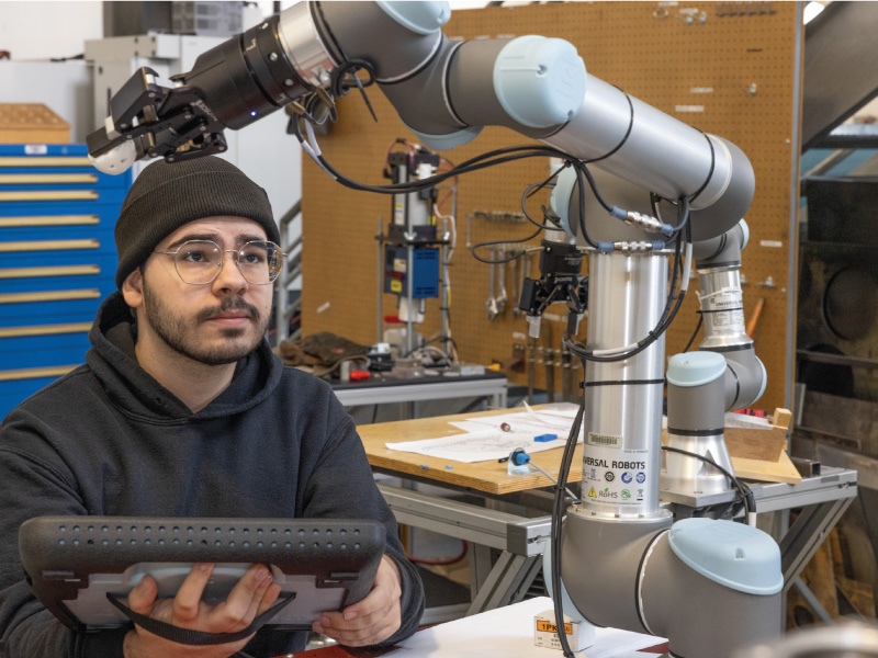 Student using a ipad to control a robot arm.