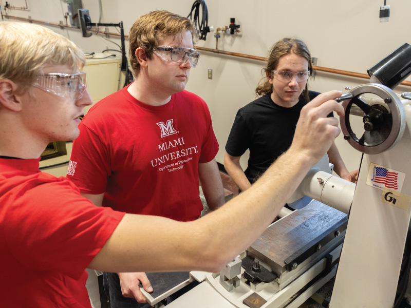 3 engineering students looking at a piece of equipment