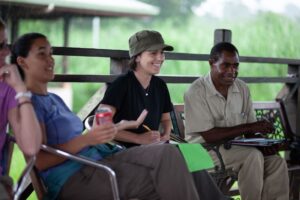 People talking while sitting on a deck in the forest